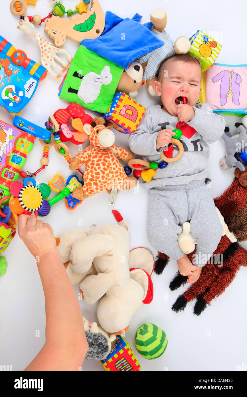 Piange il bambino che giace tra i giocattoli Foto Stock