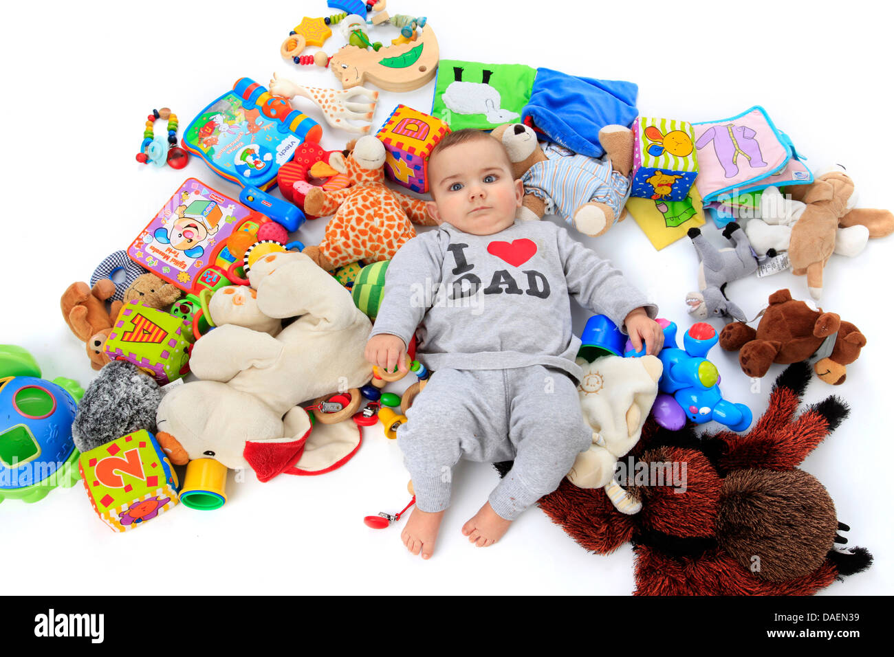 Happy baby giacente in un mucchio di giocattoli che indossa un pully con l'etichetta "Io amo papà' Foto Stock