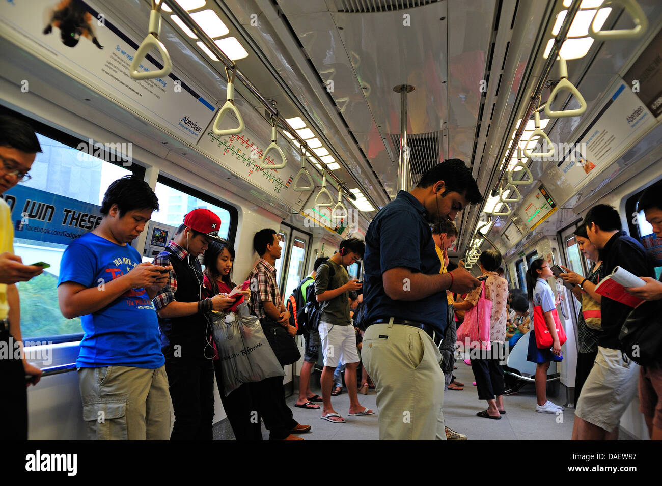 Singapore MRT. Persone che utilizzano la tecnologia sulla rete MRT Singapore Foto Stock