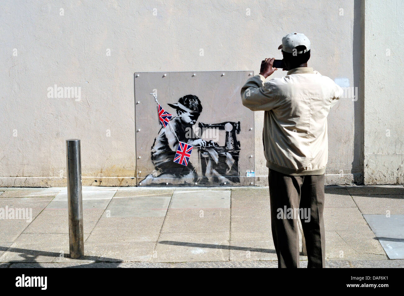 Un uomo locale fotografie Banksy murale di Turnpike Lane, London, Regno Unito Foto Stock