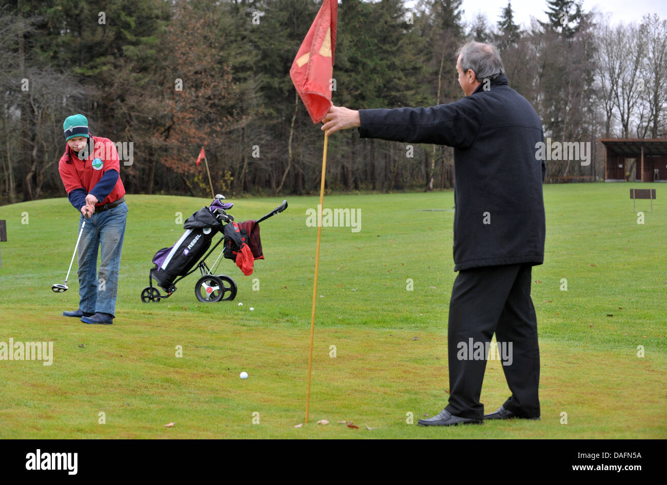 Christophe Schuler (L), il giocatore di golf con trisomia 21, putt la palla verso suo padre Dietrich, il club di vice-presidente, a Lilienthal Golf Club a Lilienthal, Germania, 28 novembre 2011. La Lilienthal club è stato il primo a rompere con la separazione dei disabili e non i giocatori. I giocatori provenienti da tutte le generazioni giocare sotto il motto "con handicap per handicap". Foto: Auto Foto Stock