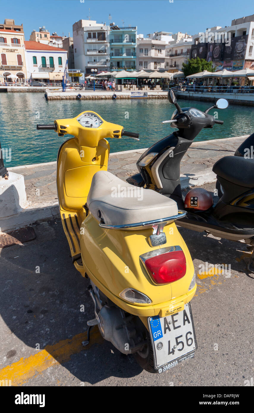 Di colore giallo brillante scooter Vespa, Agios Nikolaos Porto, Creta, Grecia Foto Stock