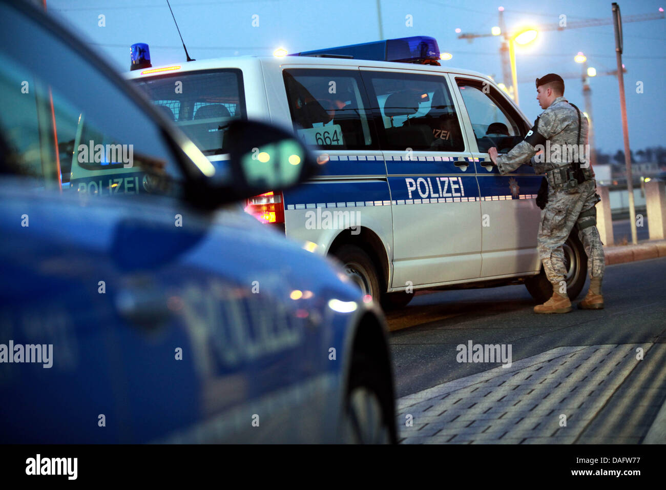 Un ufficiale della US polizia militare parla ad un ufficiale della polizia tedesca seduti in un furgone di polizia presso il Terminal 2 dell'aeroporto di Francoforte, in Germania, 2 marzo 2011. Due persone sono state uccise in un attacco contro un esercito usa autobus all'aeroporto di Francoforte. Altri due passeggeri sono stati riportati come gravemente ferito. Il presunto aggressore è stato arrestato. Foto: Frank Rumpenhorst Foto Stock