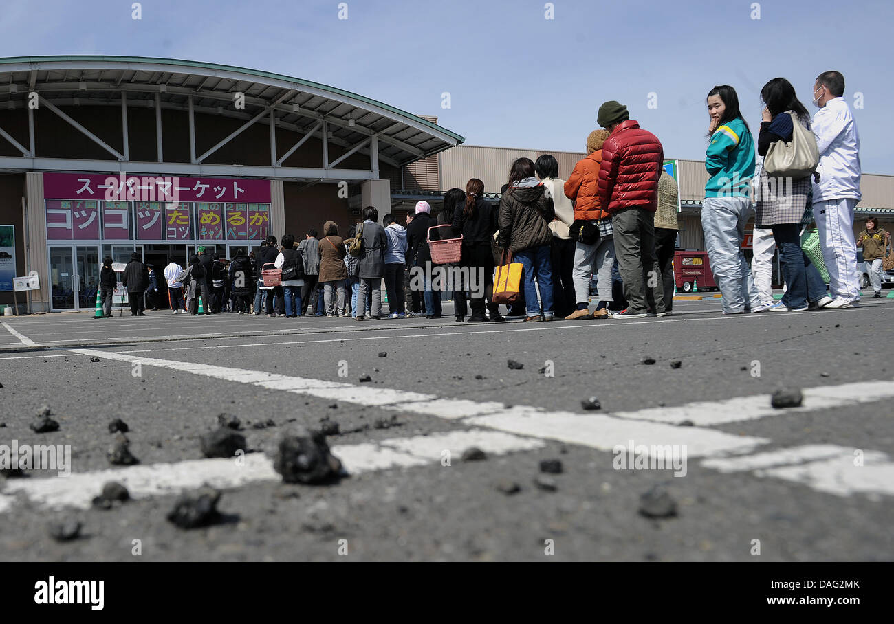 Kunden stehen am Montag (14.03.2011) vor einem teilweise zerstörten Supermarkt in Kagamiishi in Giappone Schlange. Auch in nicht unmittelbar betroffenen Teilen des Landes machen sich die Folgen der Naturkatastrophe bemerkbar. Foto: Annibale dpa Foto Stock