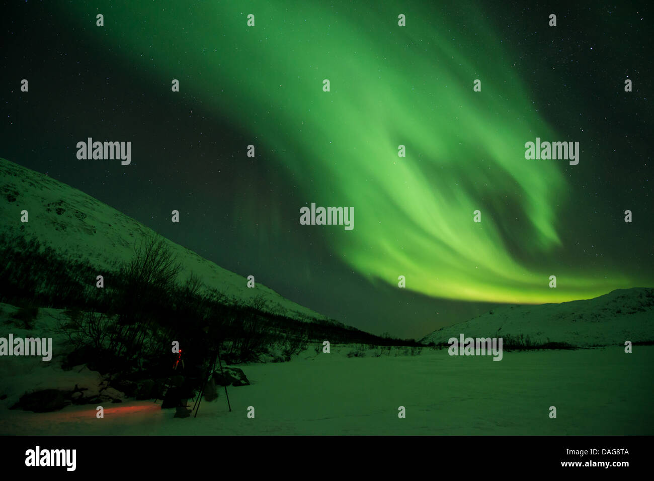 Aurora onda nella parte anteriore del cielo stellato sulla neve nella valle con un fotografo di natura delle attrezzature del nella neve, Norvegia, Troms, Kvaloea, Kattfjordeidet Foto Stock