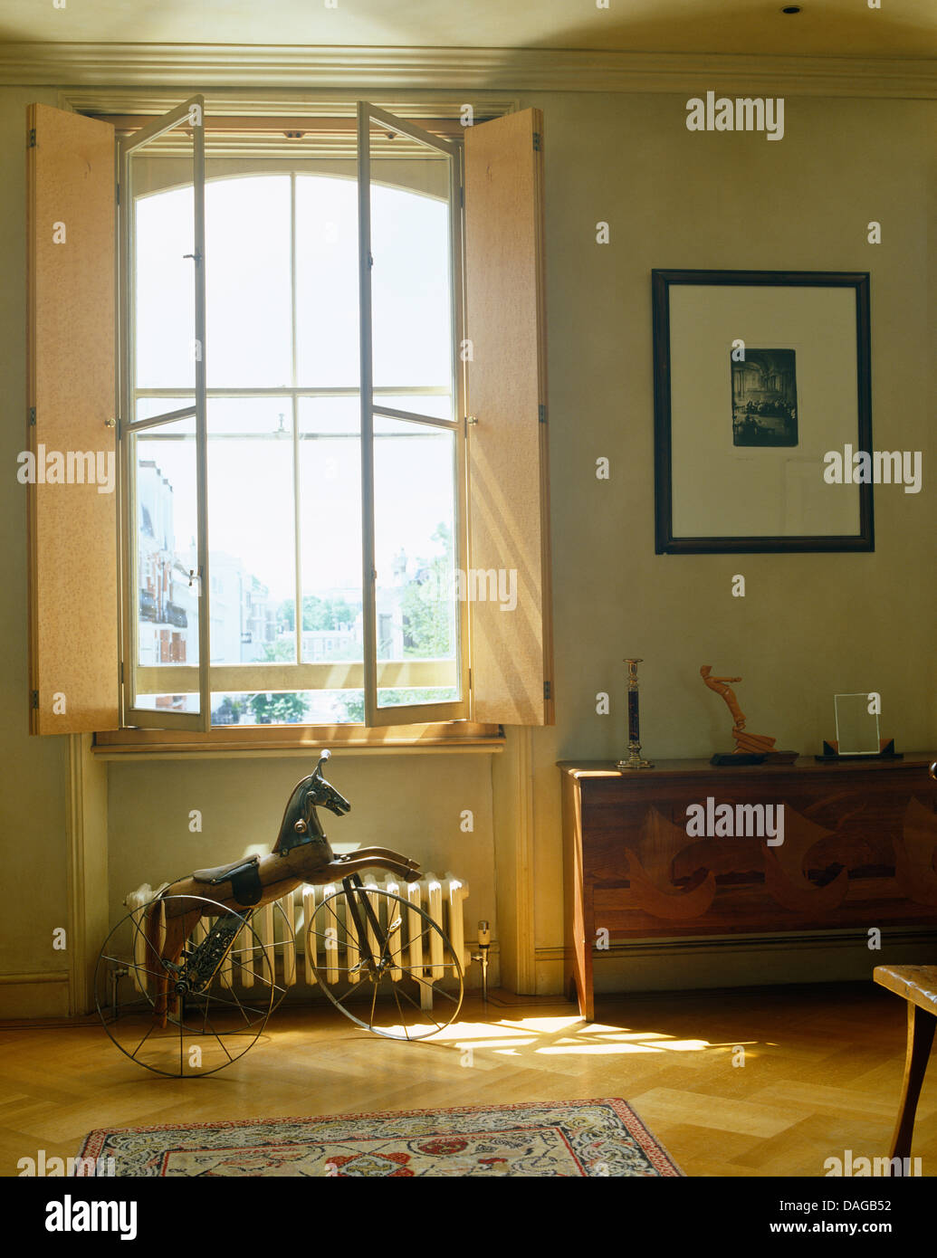 Tapparelle su finestra alta al di sopra di ruote di bicicletta cavallo di metallo in una moderna camera da letto Foto Stock