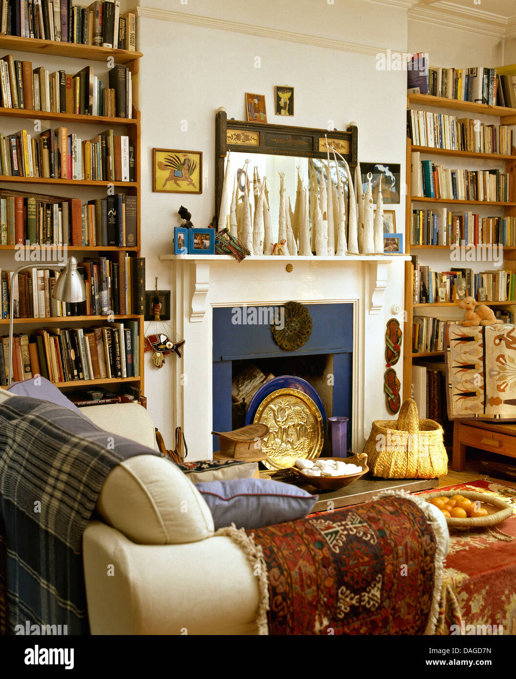 Scaffali alti su entrambi i lati di un camino in stile etnico soggiorno con  passi blu e piccolo tappeto turco sul divano color crema Foto stock - Alamy