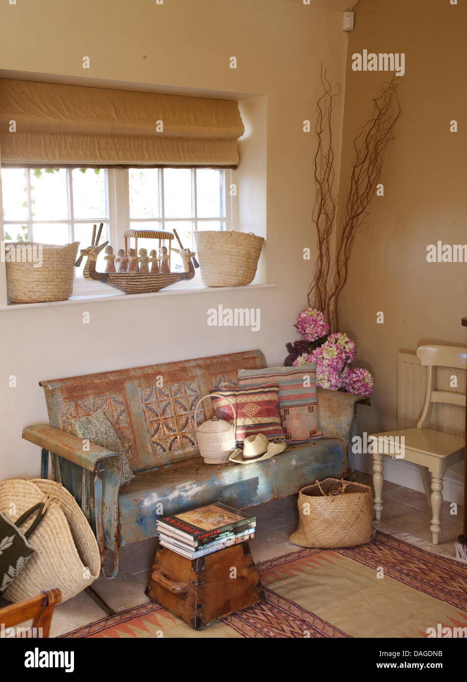 Roman cieco sulla finestra sopra di legno verniciato di stabilirsi in cottage soggiorno con insolito Sgabello in legno Foto Stock