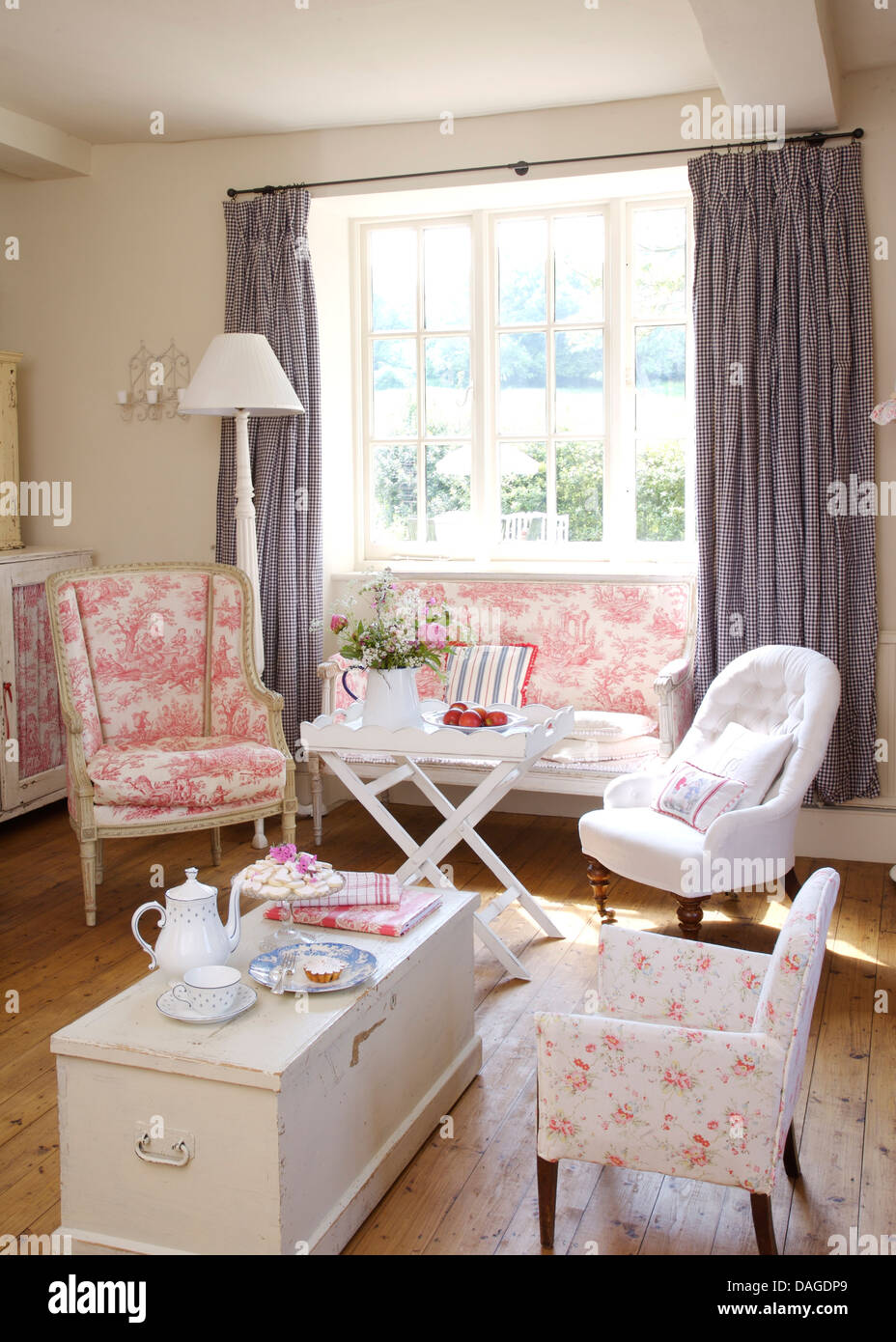 Rosa Toile de Joule sedia e un piccolo divano in cottage soggiorno con poltrona bianca e pitturato di bianco petto Foto Stock