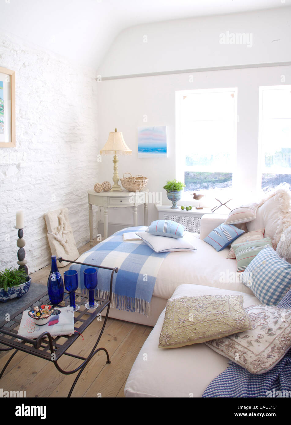 Cuscini sul divano bianco in bianco cottage costiere salotto dipinto con muri in pietra e controllati rug su bianco chaise longue Foto Stock