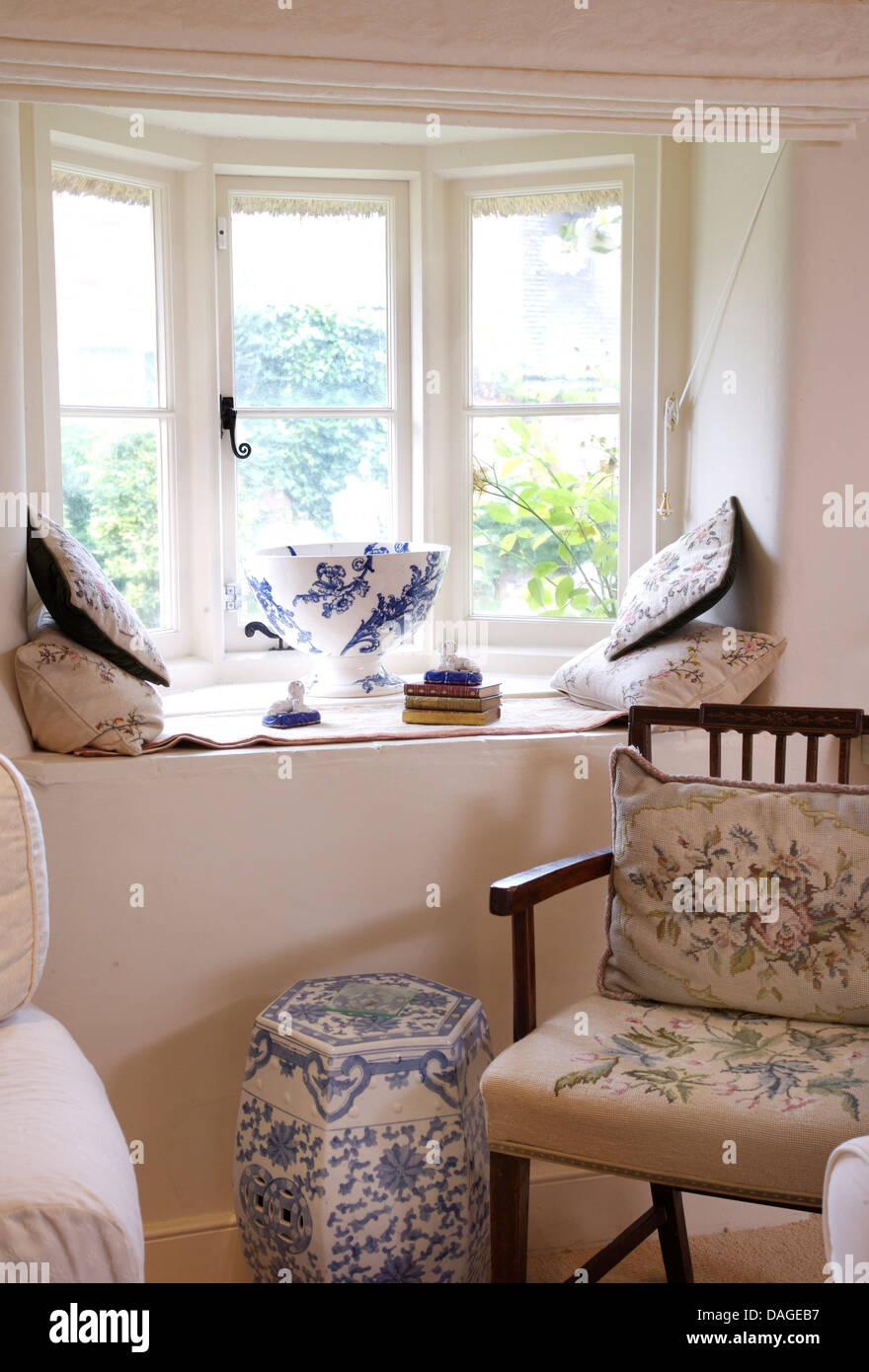 Lavorato a mano arazzo cuscino sedile e sulla sedia di legno accanto al blu cinesi+porcellana bianca Sgabello sotto la finestra cottage Foto Stock