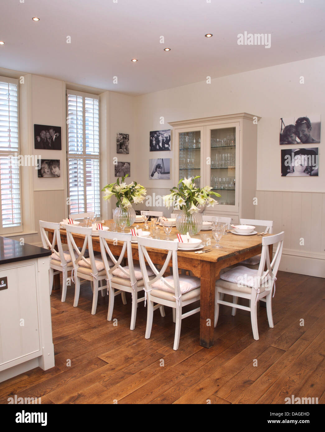 Sedie bianche in legno semplice tabella in bianca e moderna cucina sala da pranzo Camera con pavimento in legno e incorniciati nero+fotografie in bianco Foto Stock