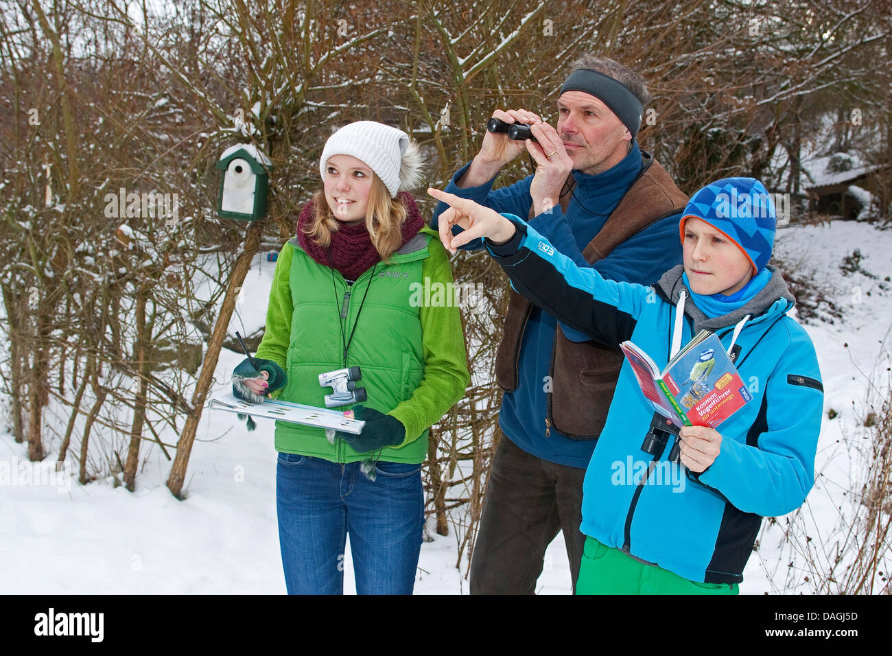 Birdwatching nel giardino in inverno, famiglia guardando gli uccelli, Germania Foto Stock
