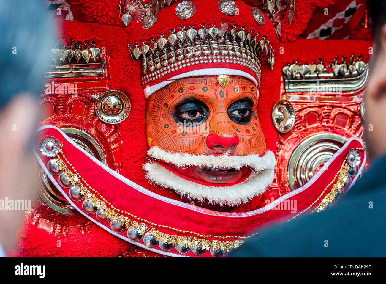 Un artista Theyyam in pieno viso make-up e costume cerimoniale durante una performance in Kannur, Kerala, India. Foto Stock