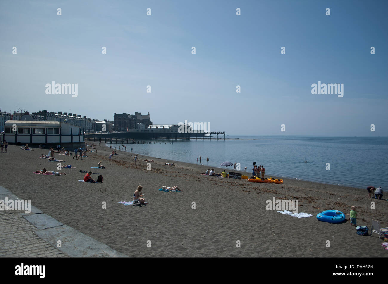 Aberystwyth, Wales, Regno Unito. 13 luglio 2013. La gente del posto e turisti godere della canicola estiva a nuoto in mare e ottenere una abbronzatura sulla spiaggia presso la località balneare di Aberystwyth. Come temperature attraverso il Regno Unito raggiunge 30 gradi Celsius, si tratta di una giornata di mare piatto, cielo sereno, gelati e creme solari come la popolazione di Aberystwyth crogiolarsi nella gloriosa Meteo weekend. Credito: Barry Watkins/Alamy Live News Foto Stock