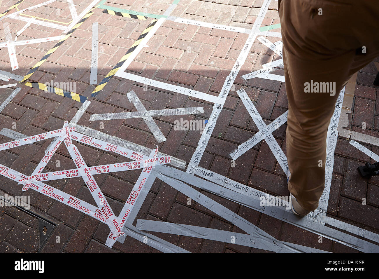 Londra, Regno Unito. Il 12 luglio 2013. Un pedone cammina su agenzia fotografica marcatura su nastro i loro punti come il mondo dei media si raccolgono al di fuori del Lindo Ala di St Marys Hospital di Londra, Inghilterra in attesa del royal baby del principe William e Kate Middleton, il Duca e la Duchessa di Cambridge. Il Lindo Ala è una struttura privata all'interno di St Marys Hospital Imperial College Healthcare NHS Trust. Credito: JoeFox/Alamy Live News Foto Stock