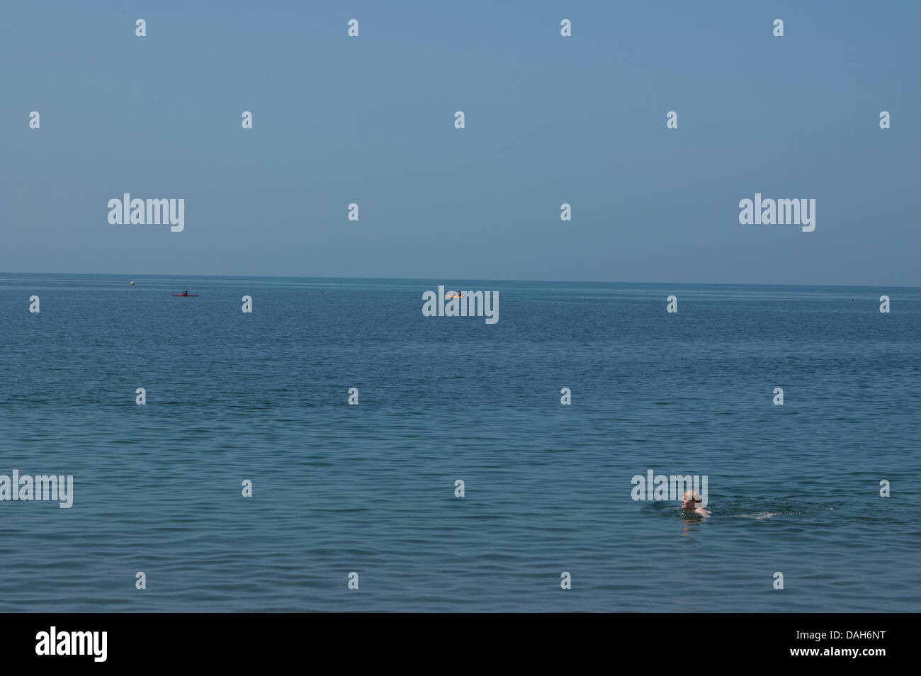 Aberystwyth, Wales, Regno Unito. 13 luglio 2013. Un nuotatore solitario e tre kayakers approfittare del clima caldo e mare piatto a Aberystwyth, in un giorno quando le temperature sono impostati per raggiungere 30 gradi Celsius in tutto il Regno Unito. Credito: Barry Watkins/Alamy Live News Foto Stock