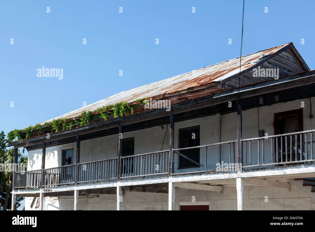 Veranda superiore balcone e rusty vitigno tetto coperto in corrispondenza di un angolo di 2° e C strade nel quartiere storico di Cedar Key, Florida. Foto Stock