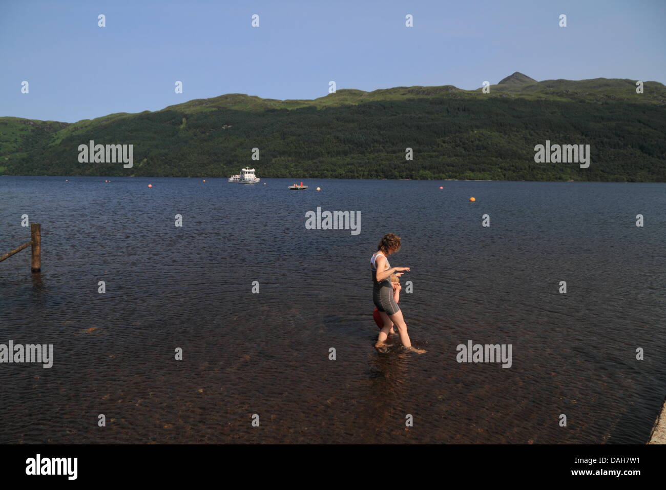 Donna e bambino sguazzare nell'acqua. Colling verso il basso. Loch Lomond, Tarbet, Scotland, Regno Unito Foto Stock