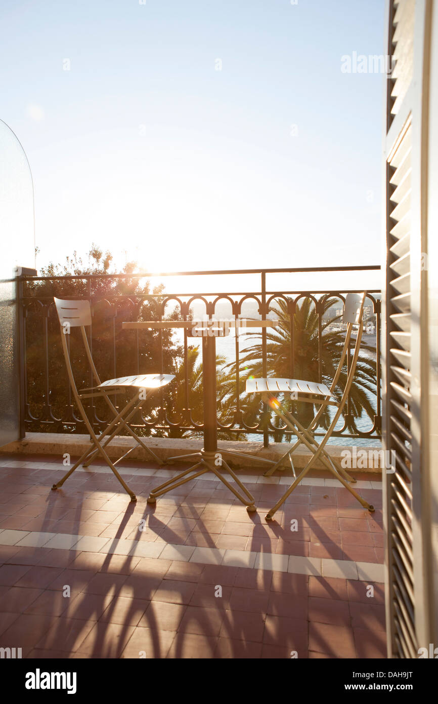 Due sedie e un tavolo su un tarrace al sole, palme. Tabella romantica per due su una soleggiata terrazza. Foto Stock