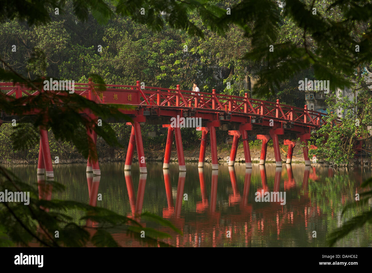 Donna che prega come lei attraversa il ponte Huc, Lago Hoan Kiem, Hanoi, Vietnam Foto Stock