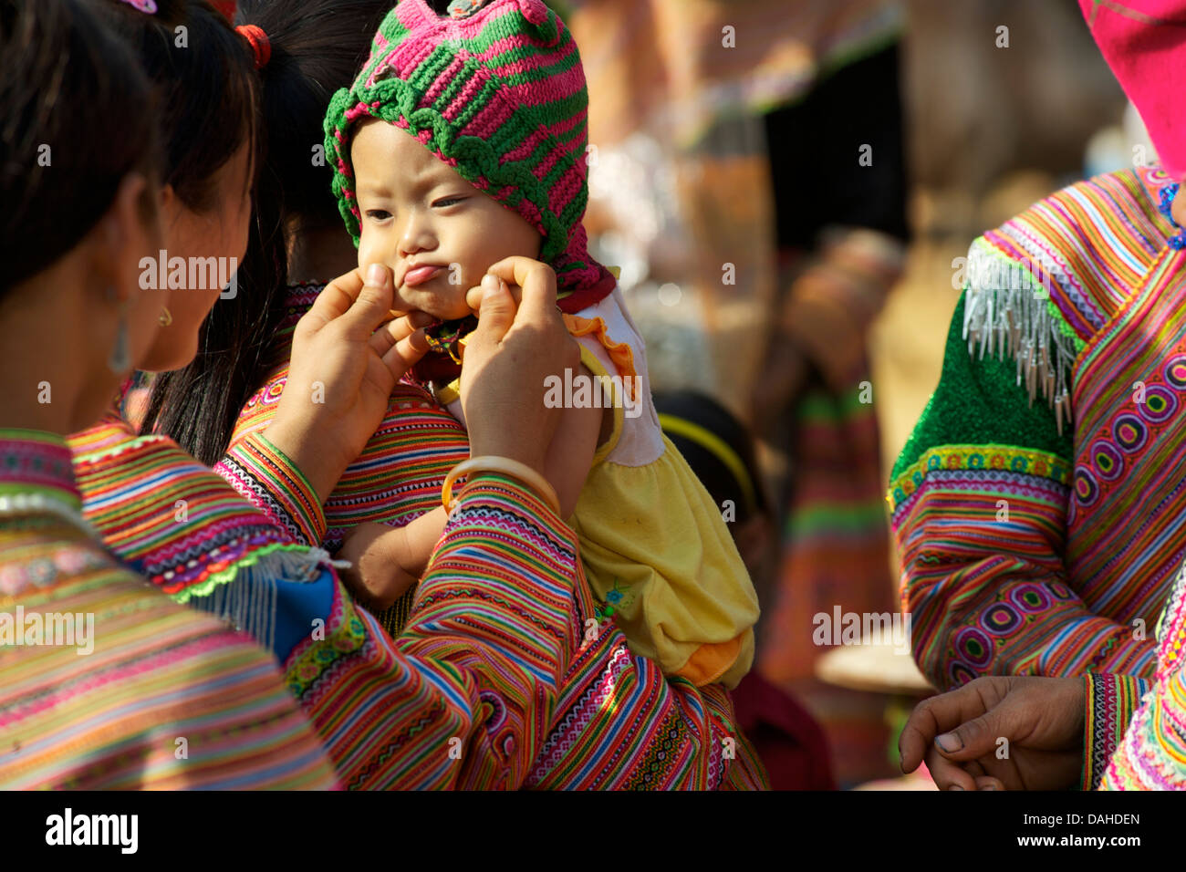 Fiore donne Hmong languono oltre il bambino. Tribale tradizionale costume. può cau, vicino a Bac Ha, Lao Cai Provincia, Vietnam Foto Stock