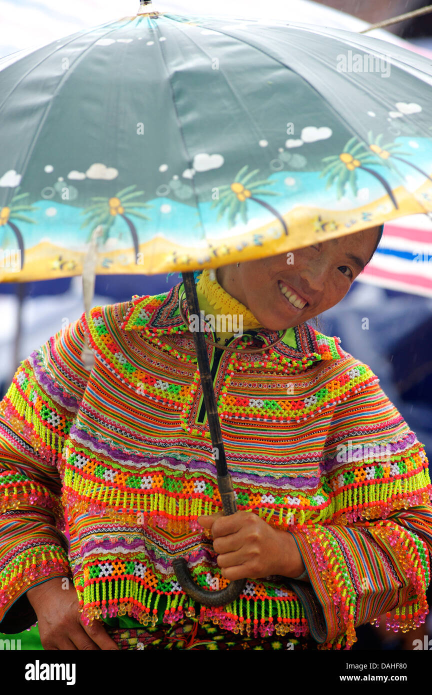 Fiore donna Hmong del peering da sotto il suo ombrello. Bac Ha mercato, Lao Cai provincia, Vietnam Foto Stock