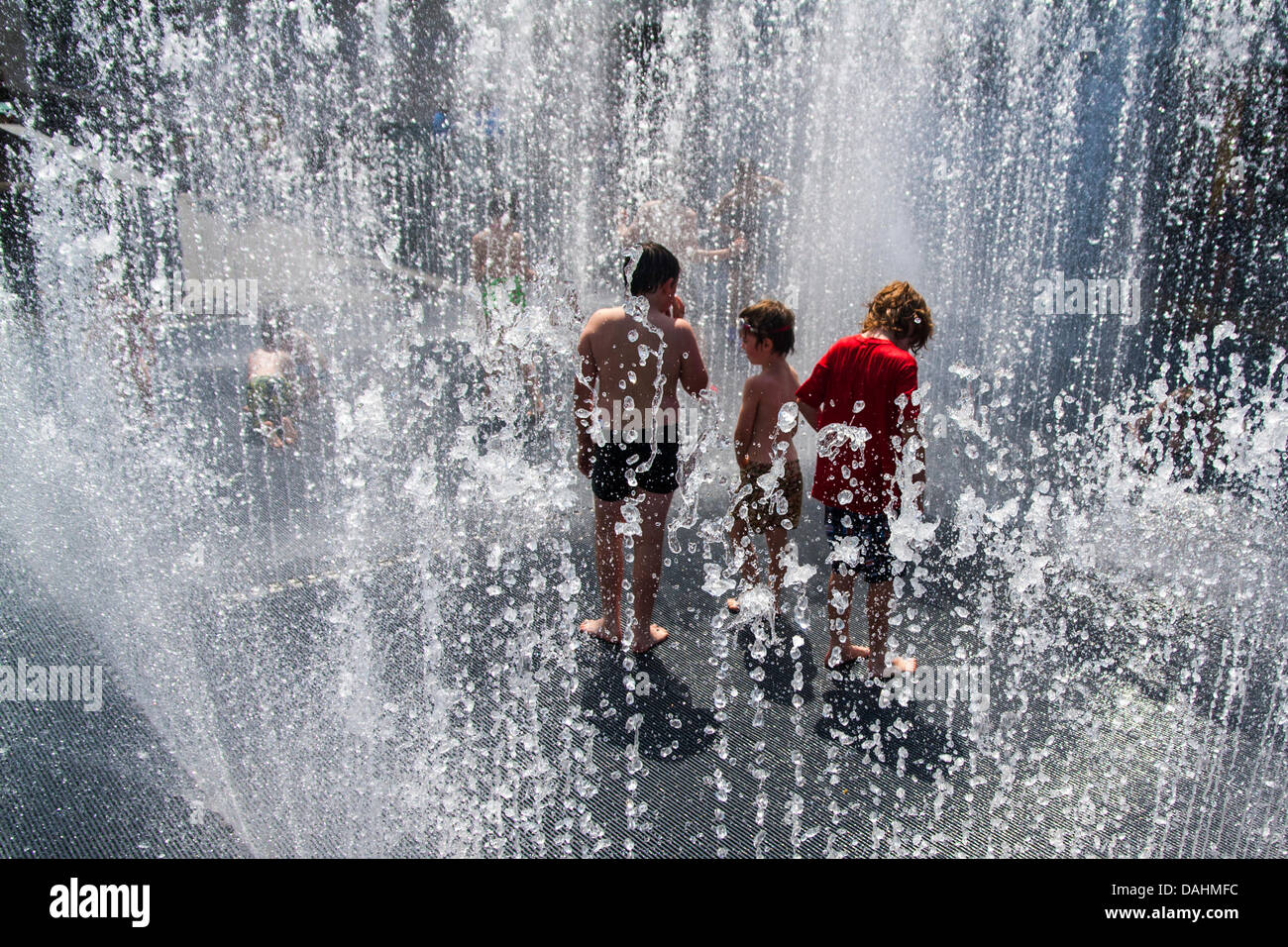 Londra, Regno Unito. 14 Luglio, 2013. I bambini godono di acqua fredda di una fontana al centro di Southbank come temperature Volate in alto venti nel centro di Londra. Credito: Paolo Davey/Alamy Live News Foto Stock