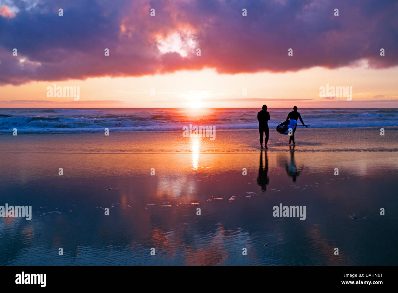 Surfers all'oceano al tramonto in Portogallo Foto Stock