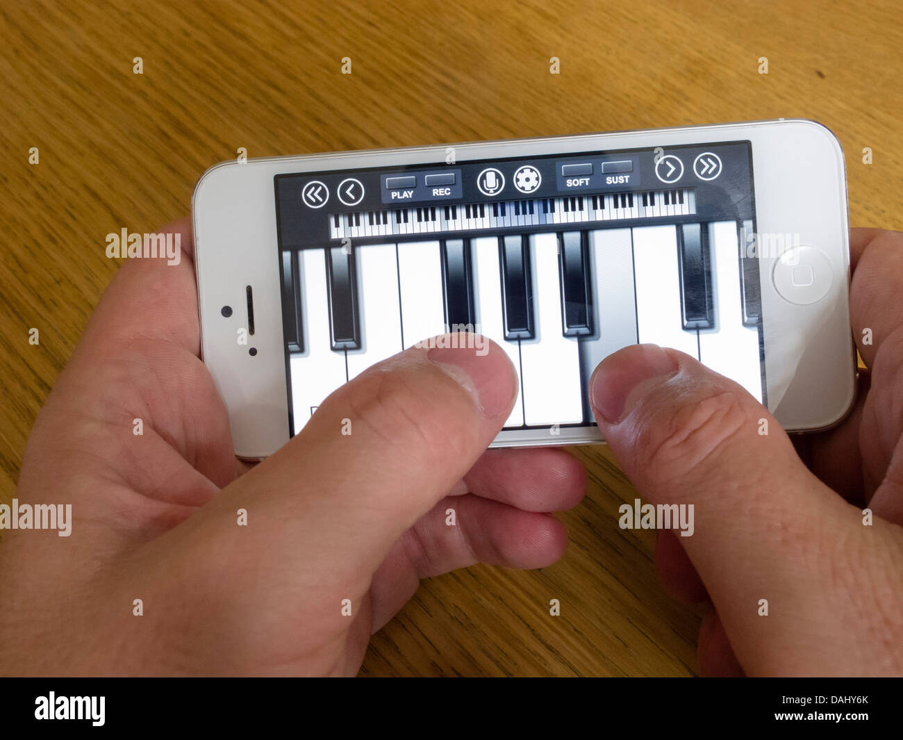 Utilizzando il bianco iPhone 5 smartphone per riprodurre la musica con pianoforte app con touch ketboard Foto Stock