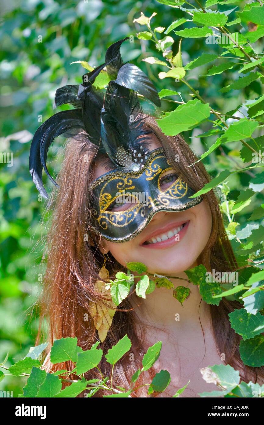 Giovani abbastanza occhi verdi che pongono la donna in estate foresta con carnevale veneziano mask Foto Stock