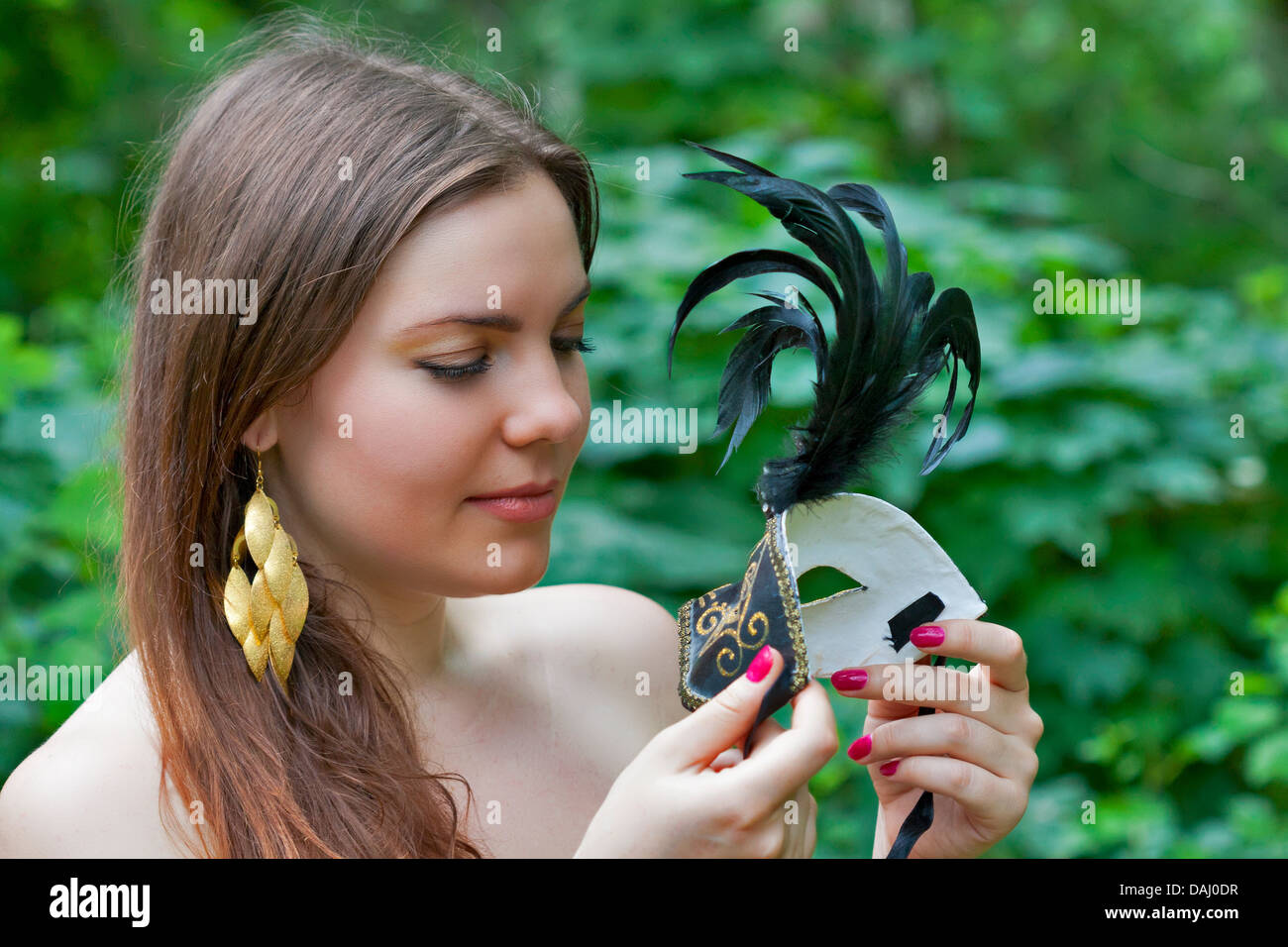 Piuttosto giovane donna che guarda sul carnevale veneziano maschera nella foresta Foto Stock