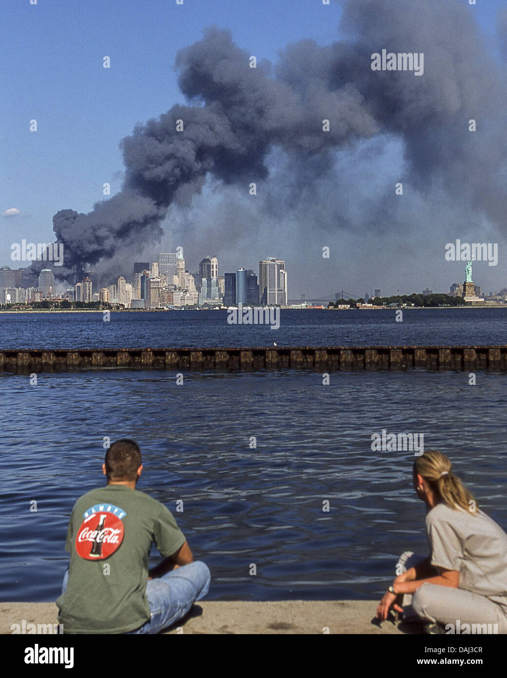 Sett. 11, 2001 - New York New York, USA - Due storditi gli spettatori attraverso il fiume Hudson in New Jersey, guardare come una densa colonna di fumo scuro e detriti flutti su Manhattan e la Statua della Libertà in N.Y. harbour [destra], da caduti twin 110-storia torri del World Trade Center dopo i terroristi si è schiantato due aerei dirottati in essi l'11 settembre 2001. (Credito Immagine: © Arnold Drapkin/ZUMAPRESS.com) Foto Stock