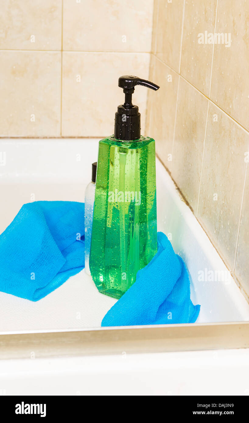 Foto verticale di tall verde gel doccia bottiglia con gocce di acqua di lavaggio, panno e una piccola bottiglia di balsamo per capelli con doccia Foto Stock