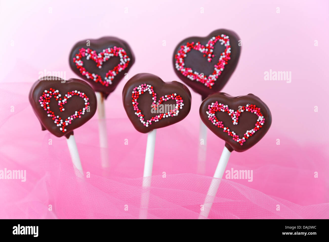 Ricoperta di cioccolato pops torta a forma di cuore con spruzzi di rosa per la festa di San Valentino Foto Stock