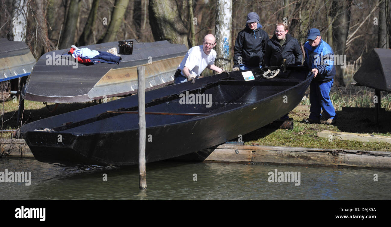 Tre uomini lancio di una chiatta sul fiume su un canale nella pittoresca regione Spreewald vicino alla città di Luebbenau, Germania, 24 marzo 2011. Foto: Patrick Pleu Foto Stock