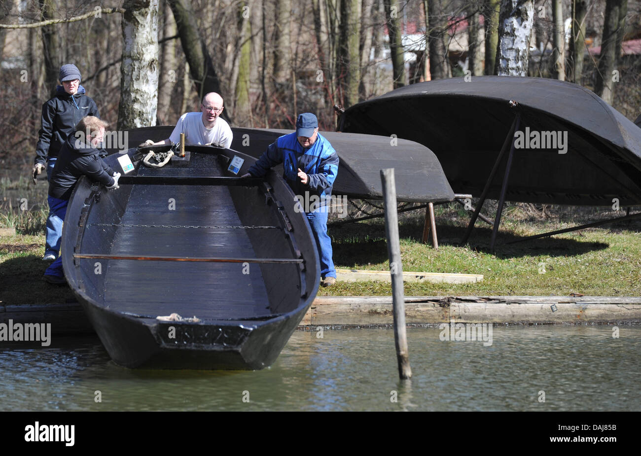 Tre uomini lancio di una chiatta sul fiume su un canale nella pittoresca regione Spreewald vicino alla città di Luebbenau, Germania, 24 marzo 2011. Foto: Patrick Pleu Foto Stock