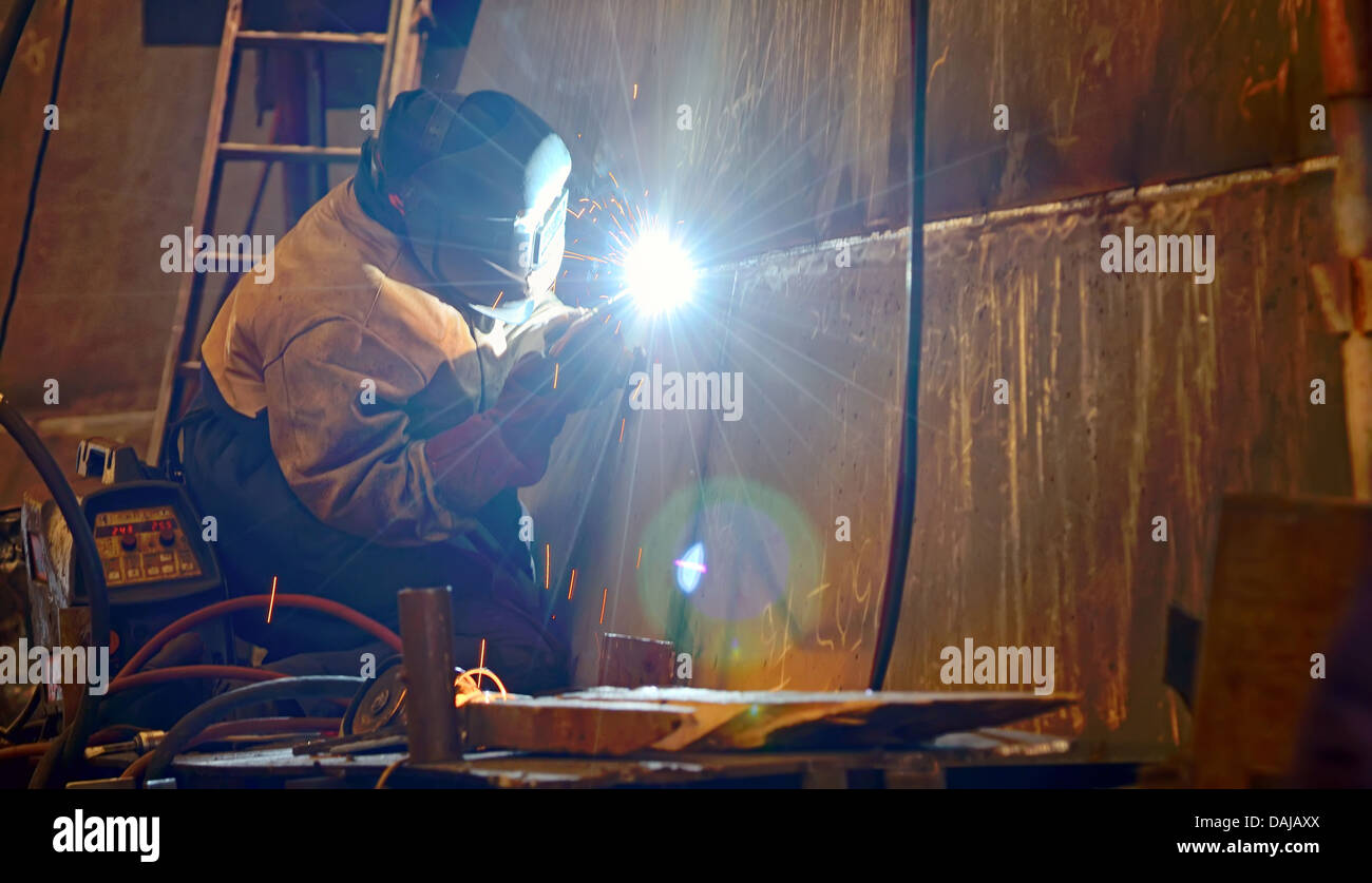 Un saldatore a lavorare presso il cantiere di costruzione di una nave Foto Stock