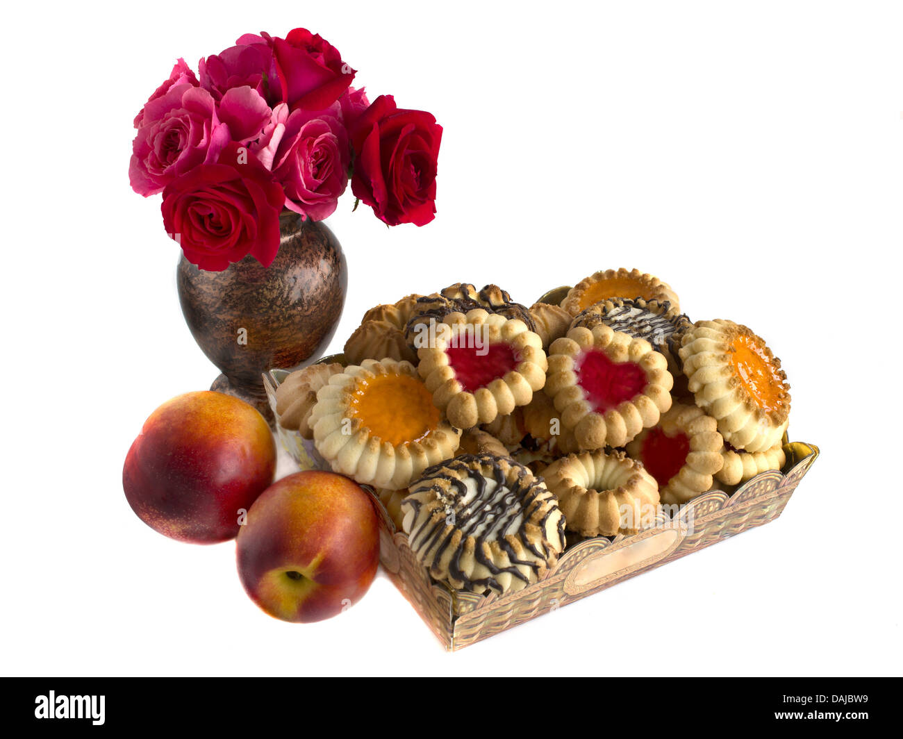 Biscotti in una scatola, nettarine e pesche noci e un mazzo di rose Foto Stock