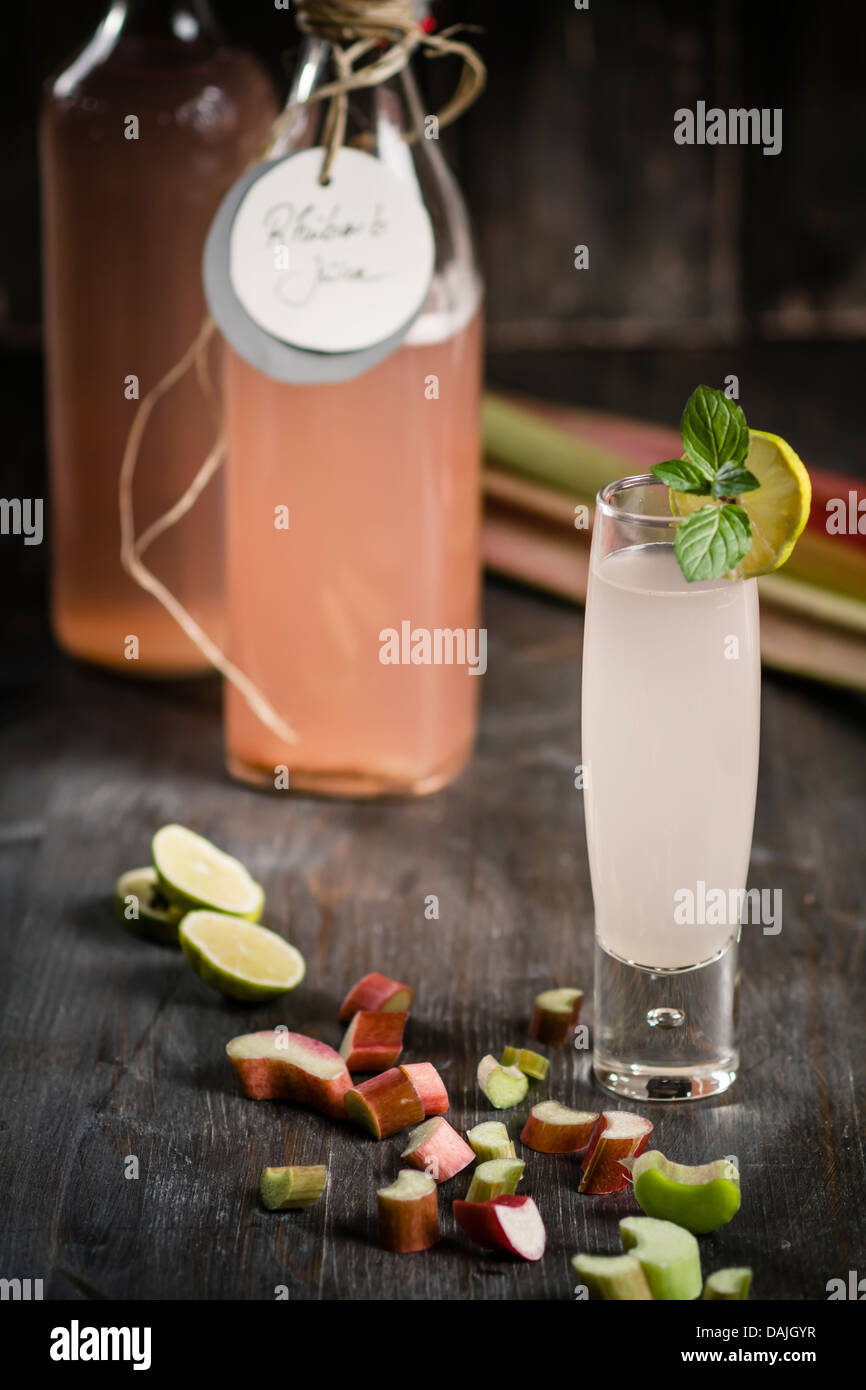 Bicchiere di rabarbaro con succo di rabarbaro flacone e pezzi di rabarbaro sul tavolo di legno, close up Foto Stock