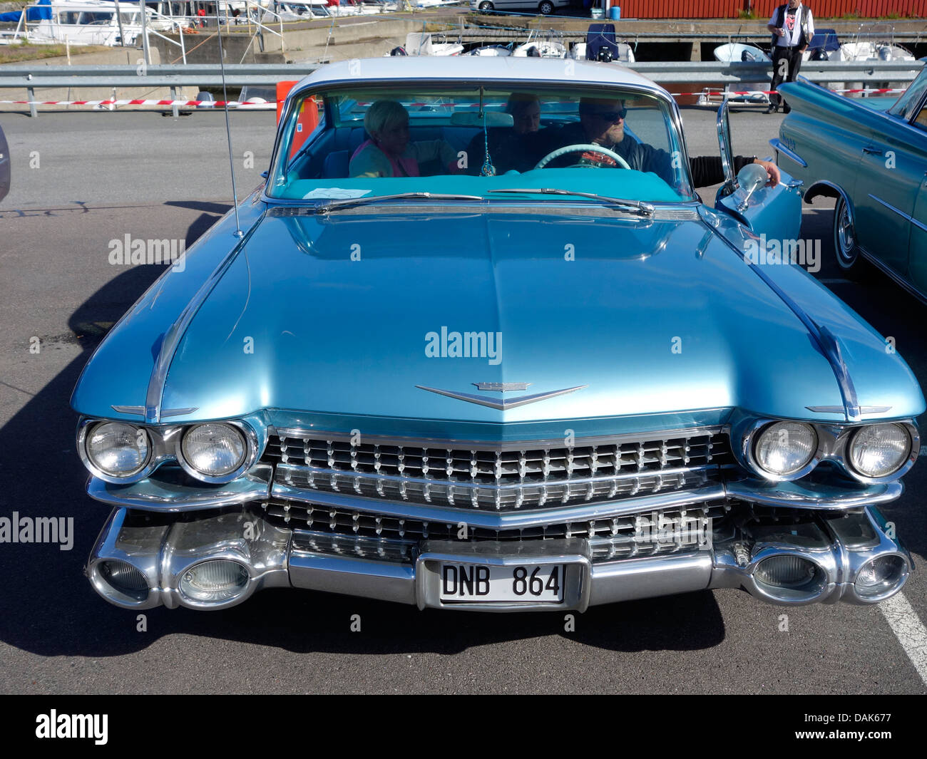 Vista frontale di un auto classica CADILLAC DE VILLE DA 1959th in un parcheggio con un Autista e passeggeri in esso. Foto Stock