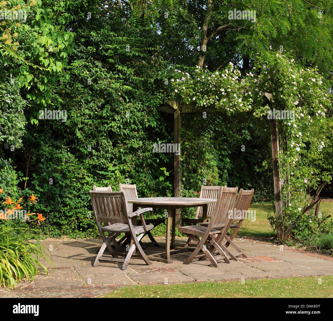 Inglese torna giardino patio con tavolo e sedie e rose arco coperto Foto Stock