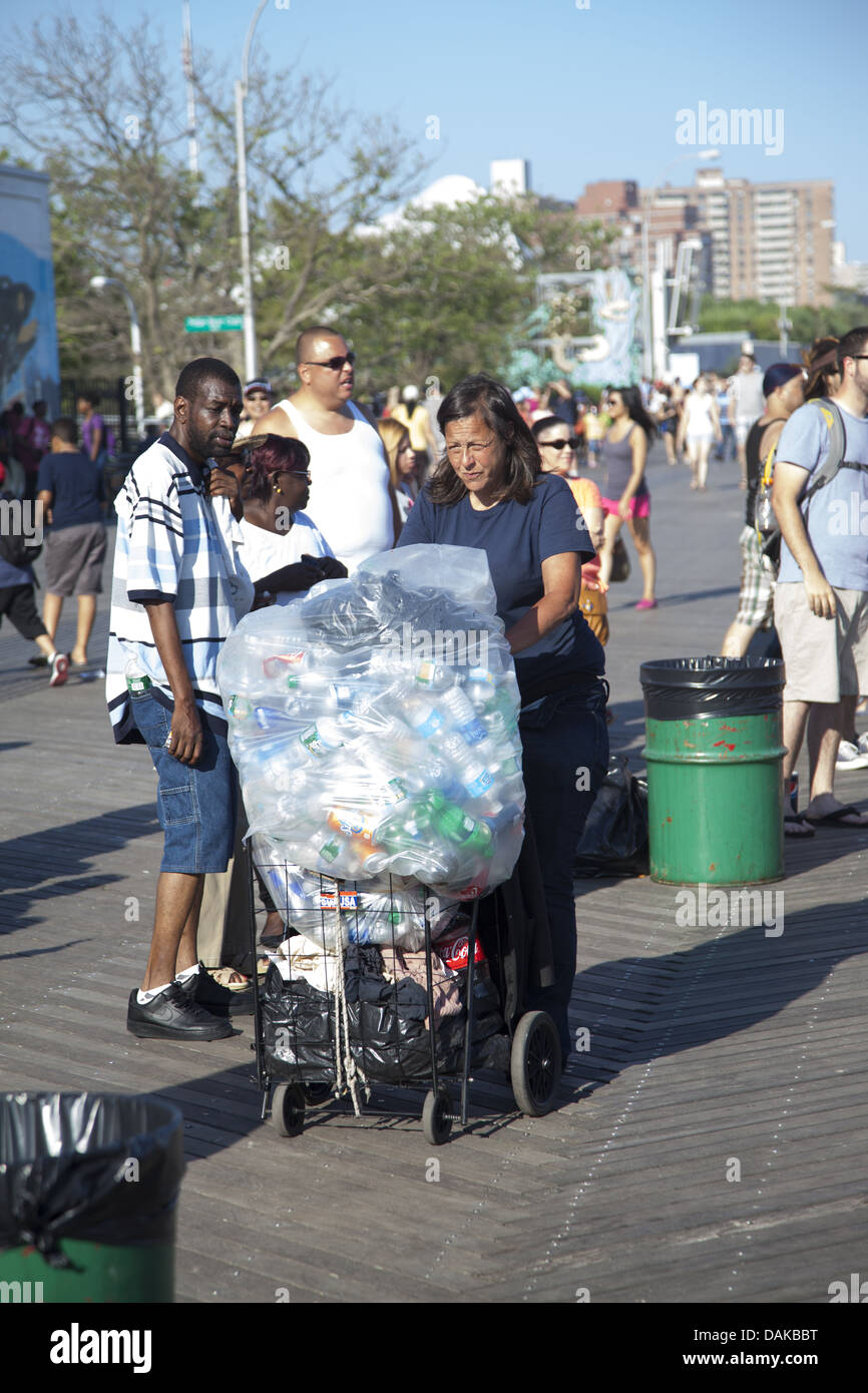 La persona povera scrounging per le lattine e le bottiglie sulla passerella a Coney Island per raschiare insieme alcuni soldi. Foto Stock