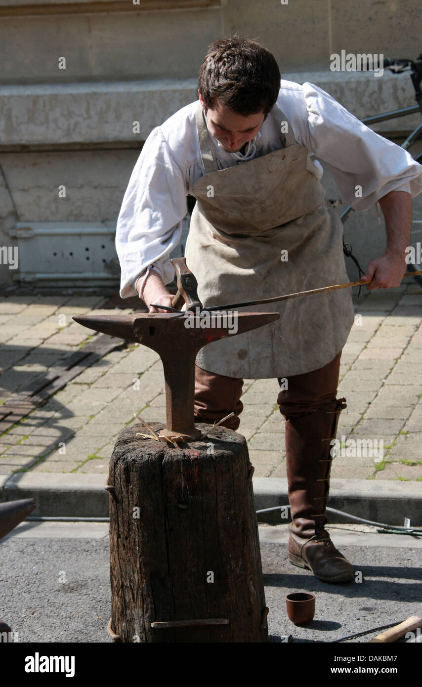 Fabbro dimostrando metodo medievale di lavorazione del ferro, Giovanna d'arco Festival, Reims, Marne, Champagne-Ardenne, Francia. Foto Stock