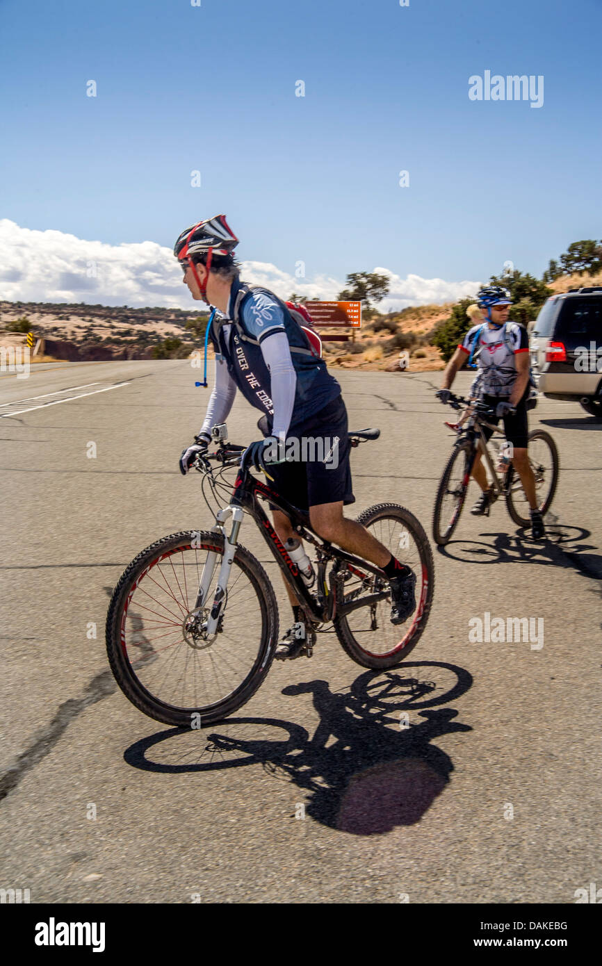 Indossare i caschi e abbigliamento specializzato, due italiani mountain bicycle club membri controllare il traffico nel Parco Nazionale di Canyonlands. Foto Stock