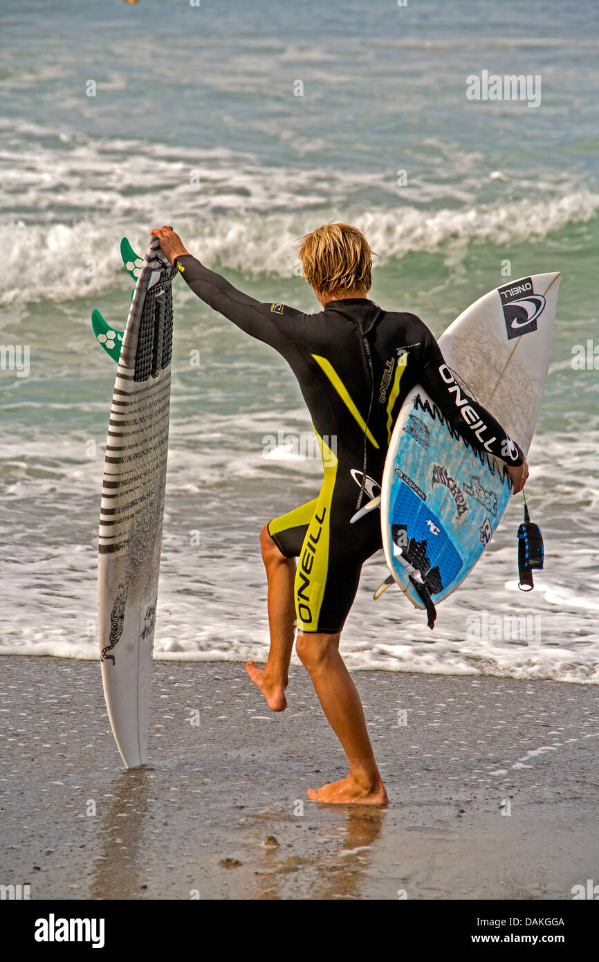 Un ragazzo adolescente membro del San Clemente, CA, Alta Scuola surf team si prepara a inserire l'Oceano Pacifico presso la città di spiaggia. Foto Stock