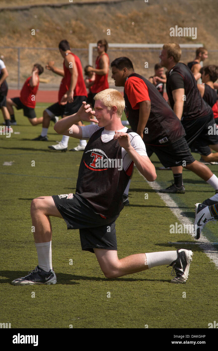 Multi-etnico di alta scuola atleti agile con esercizi di flessibilità come cominciano la molla pratica di gioco del calcio in California. Foto Stock