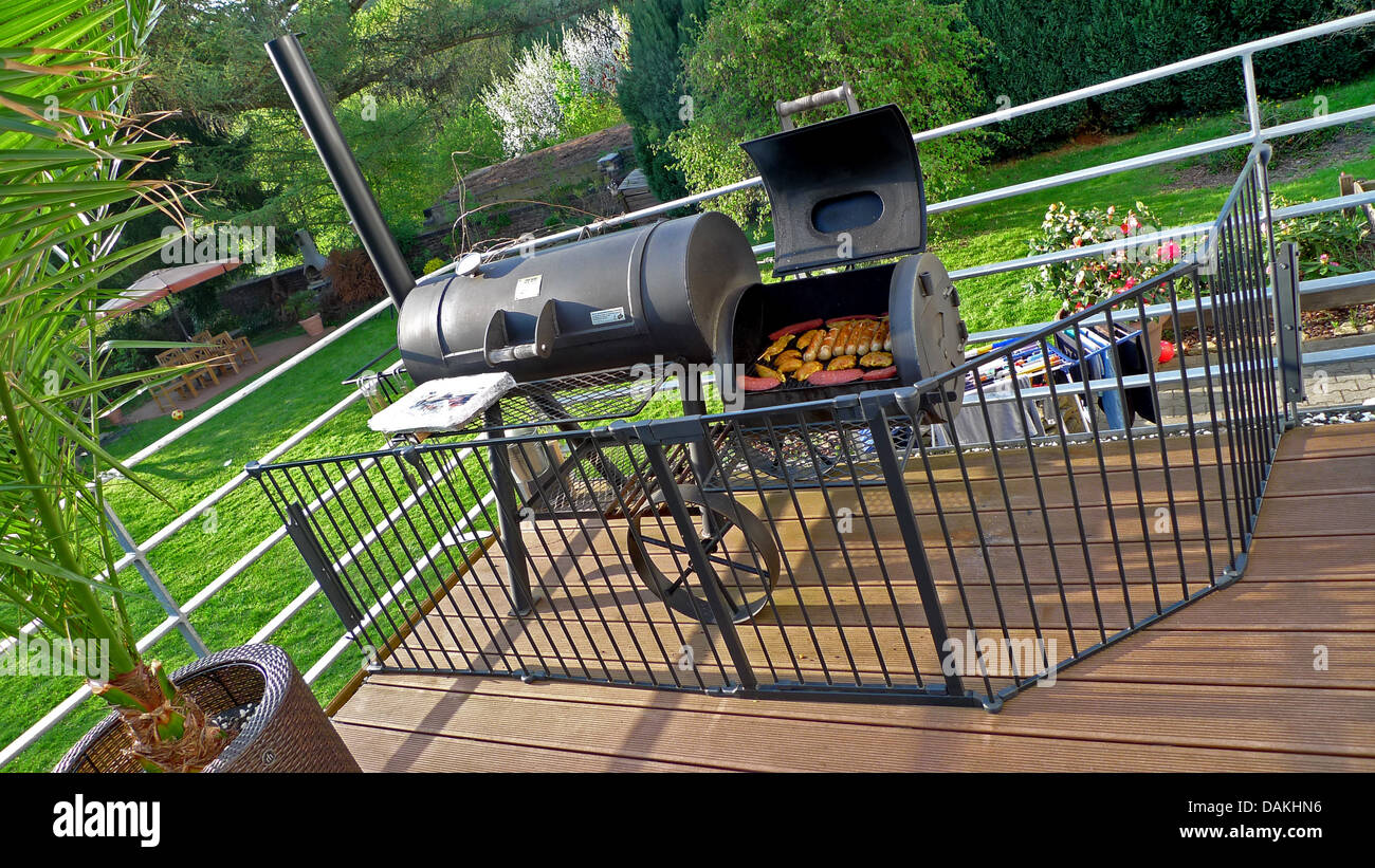 Grill pieno di carne e salsicce e circondata da un recinto per bambini protezione su una veranda Foto Stock