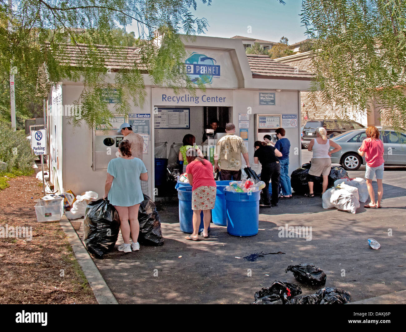 Multi-etnico residenti locali in Aliso Viejo, CA, portare in metallo, vetro e plastica rifiutare a un centro di riciclaggio. Foto Stock