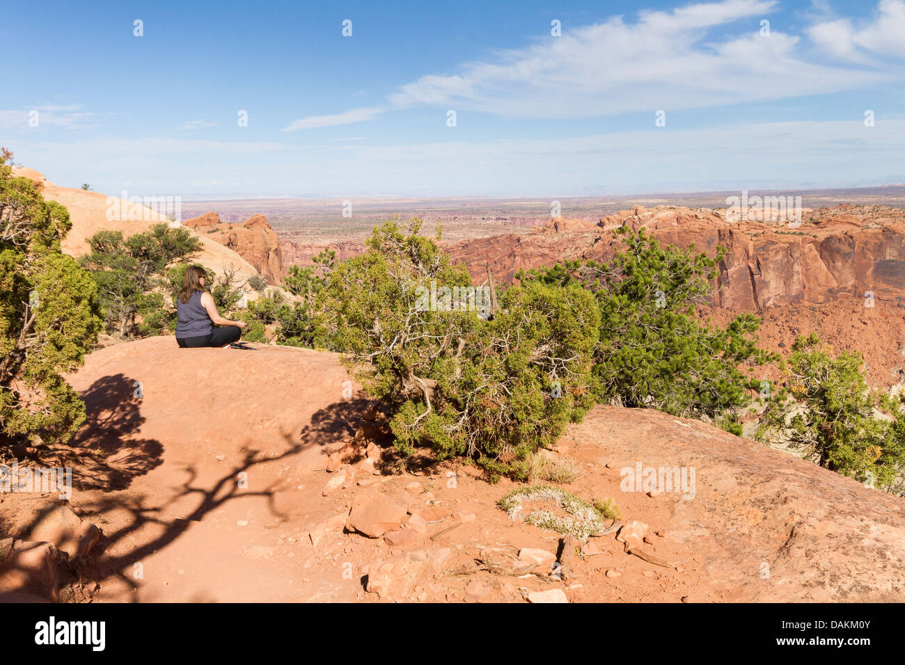 Donna rilassarsi sul bordo del canyon lungo il sentiero nel Parco Nazionale di Canyonlands, Utah Foto Stock